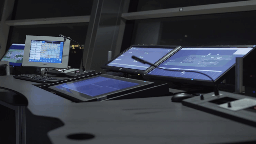 Five Garex screens are lit up in a dark room.