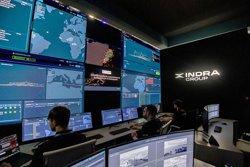 Operators sit in front of a wall of screens in an Indra control room.