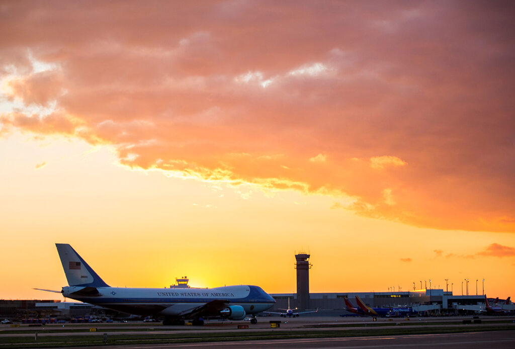 An orange sunset sits over a plane at the Dallas airport.