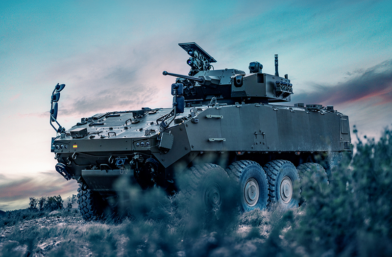 A tank sits in a field against a teal sky.