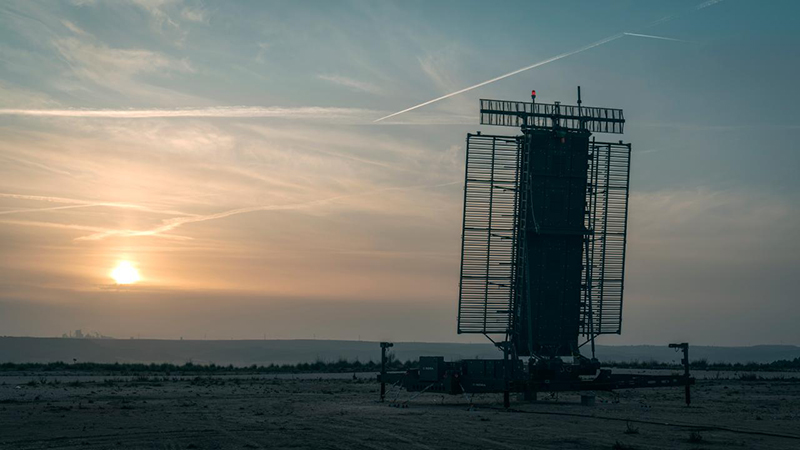 A scenic view of a defense radar as the sun rises over a flat plain.