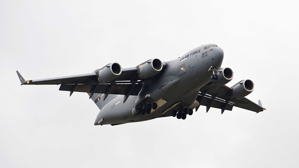 U.S. fighter jet flies in a gray sky.
